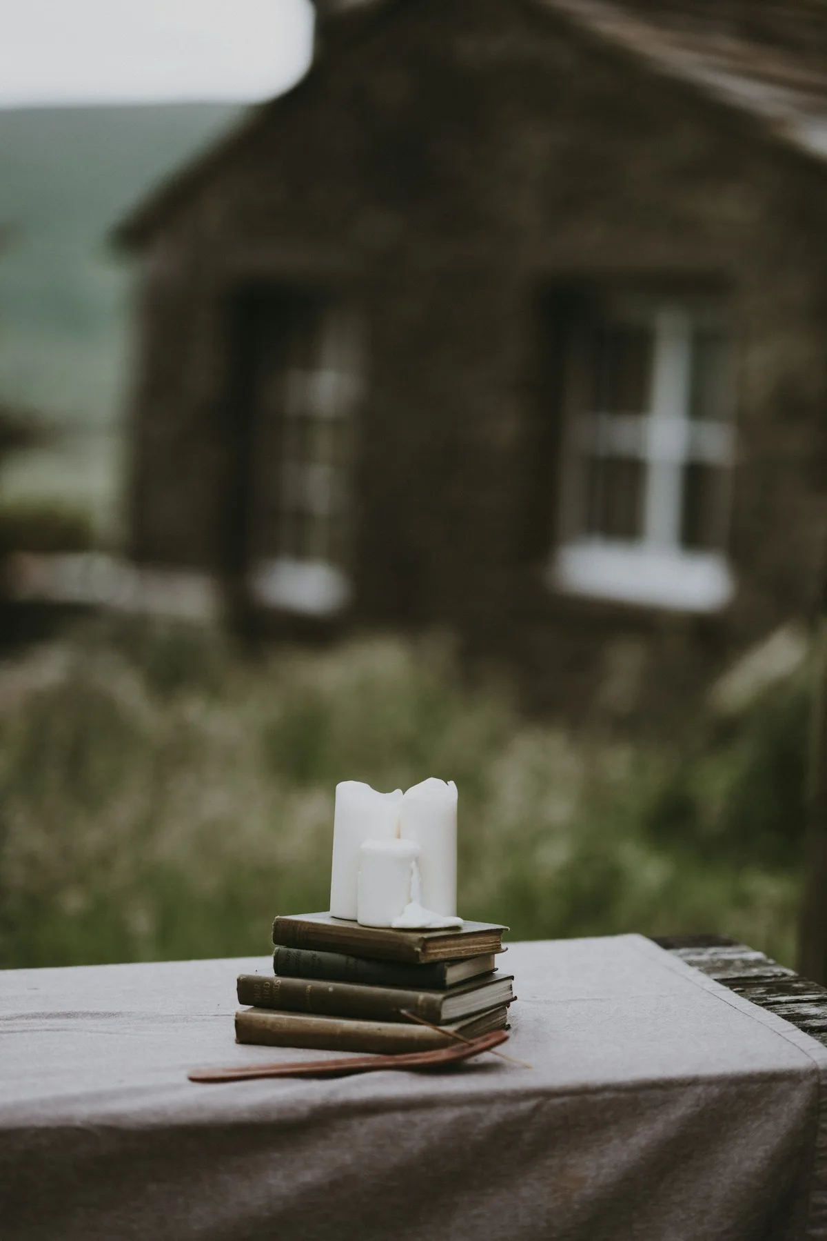 A white pillar candle arranged with books outdoors